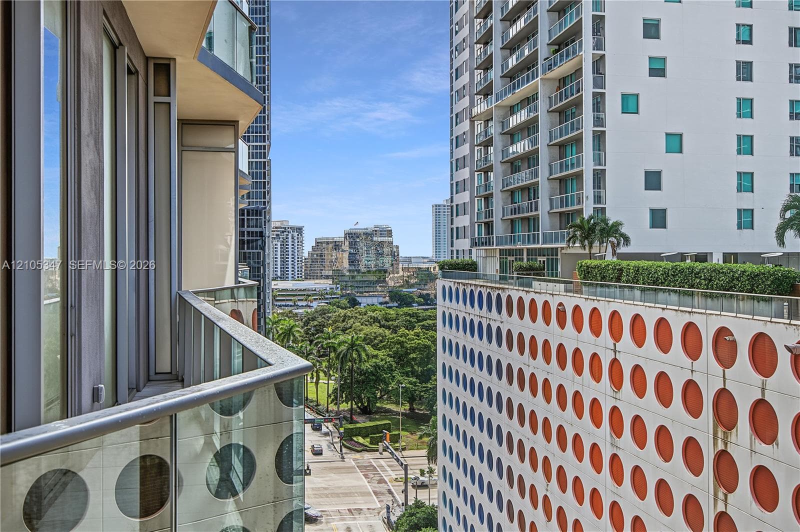Balcony with glass and metal railing, offering urban and green space elements
