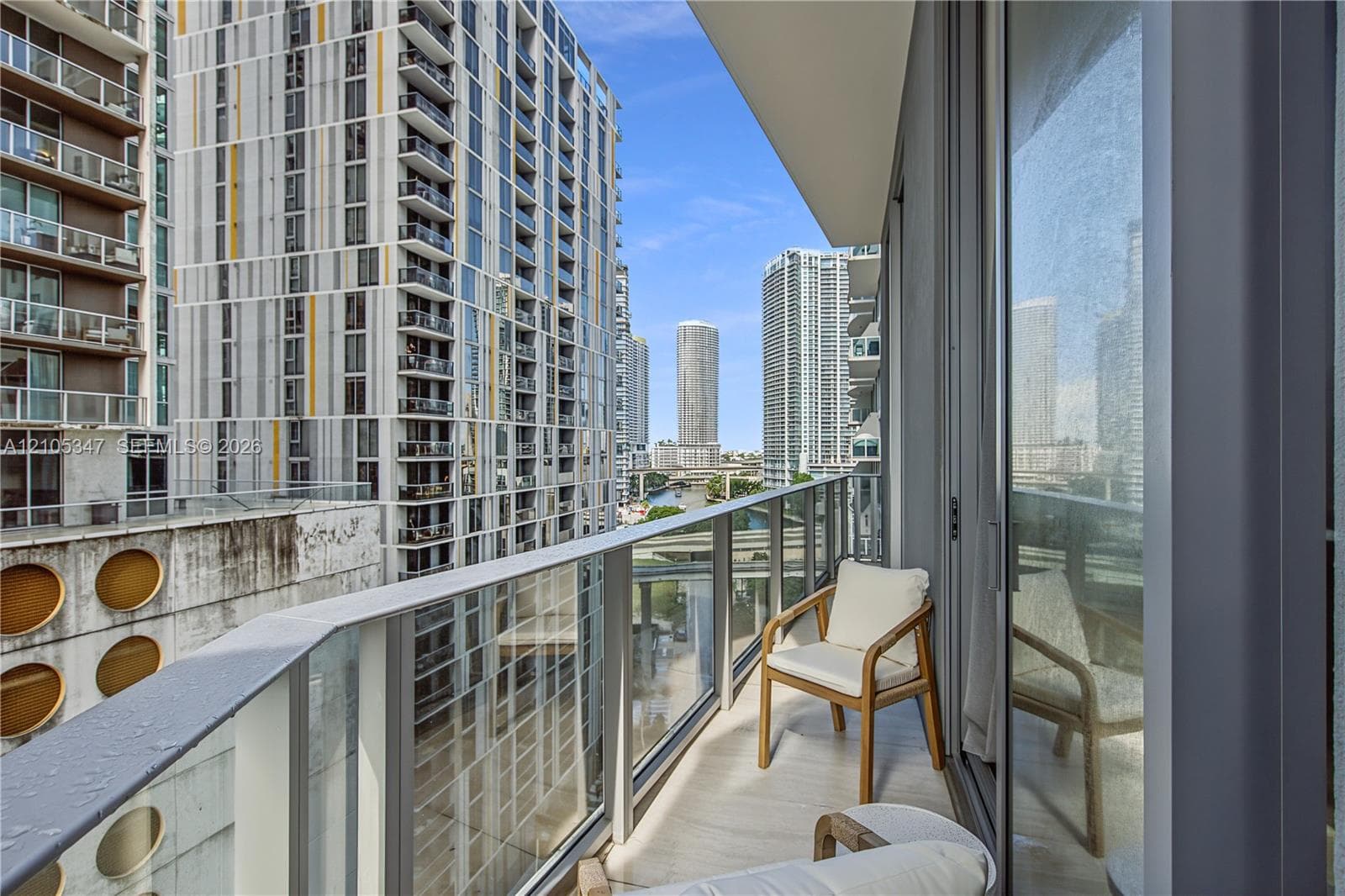 Balcony featuring a glass railing, cityscape backdrop, and water canal