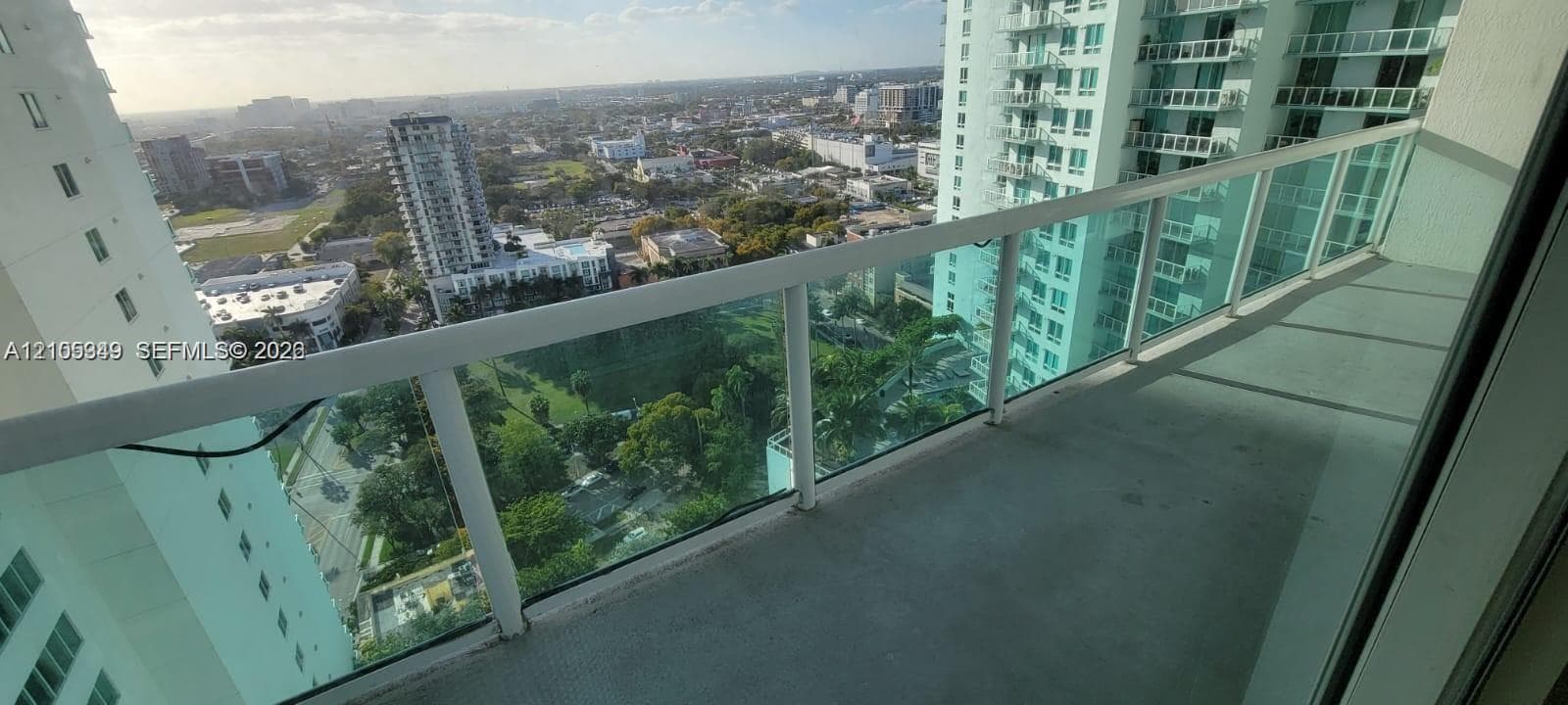 Spacious balcony with a glass and metal railing, offering panoramic urban scenery