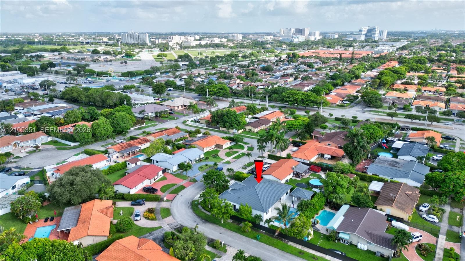Aerial perspective of a property featuring a multi-pitched roof, swimming pool, and mature perimeter landscaping