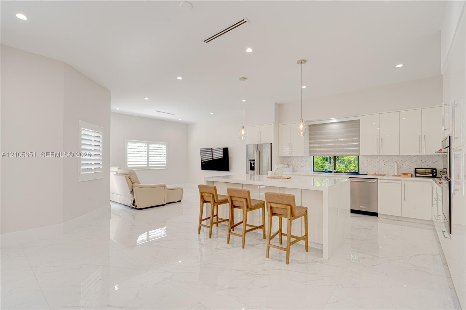 Kitchen featuring high-gloss cabinetry, stone-finish countertops, waterfall-edge island, polished tile flooring, and recessed lighting