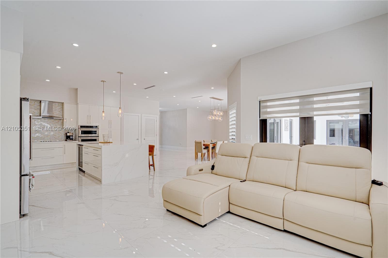 Open concept interior featuring high-gloss large-format tile flooring, stone-finish kitchen island, recessed lighting, and stainless steel built-in appliances