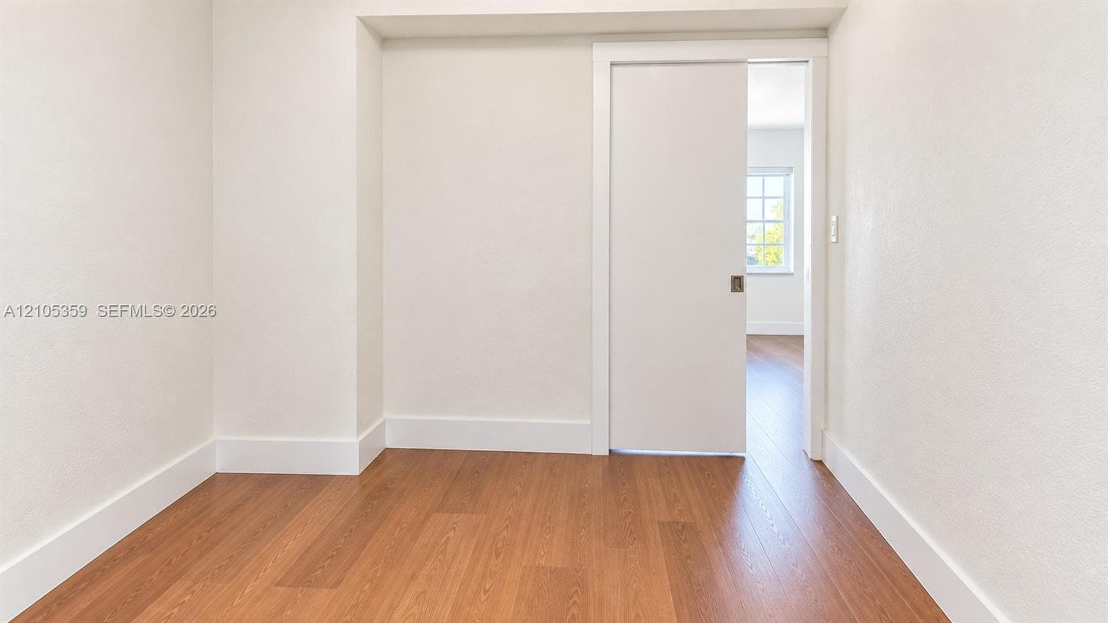 Wood-finish flooring, white walls, and a sliding pocket door with a recessed handle