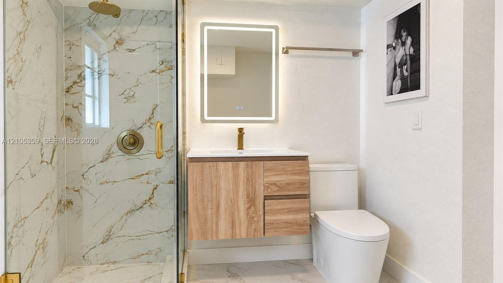 Walk-in shower with clear glass enclosure and gold-toned fixtures
