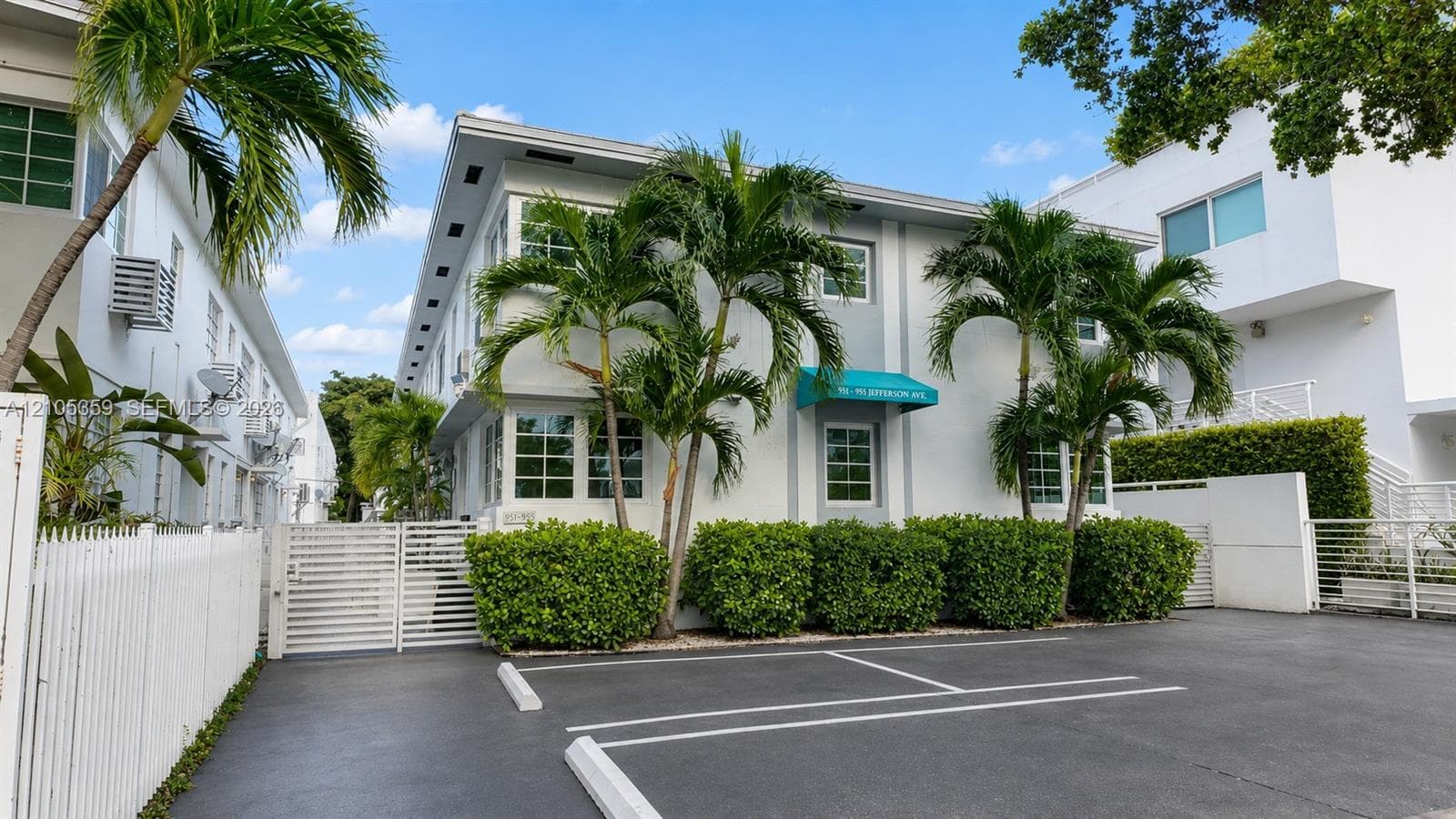 White stucco exterior with a green awning and multiple windows