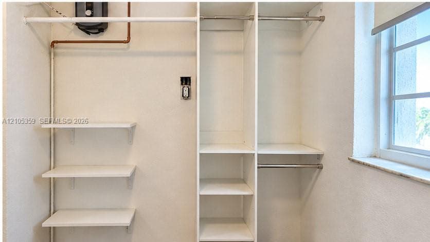 Built-in shelving, hanging rods, and a window with a stone sill