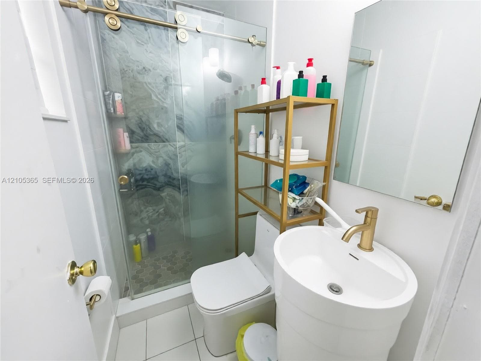 Glass-enclosed shower with a sliding barn door system, featuring dark patterned wall tiles and a mosaic tile floor