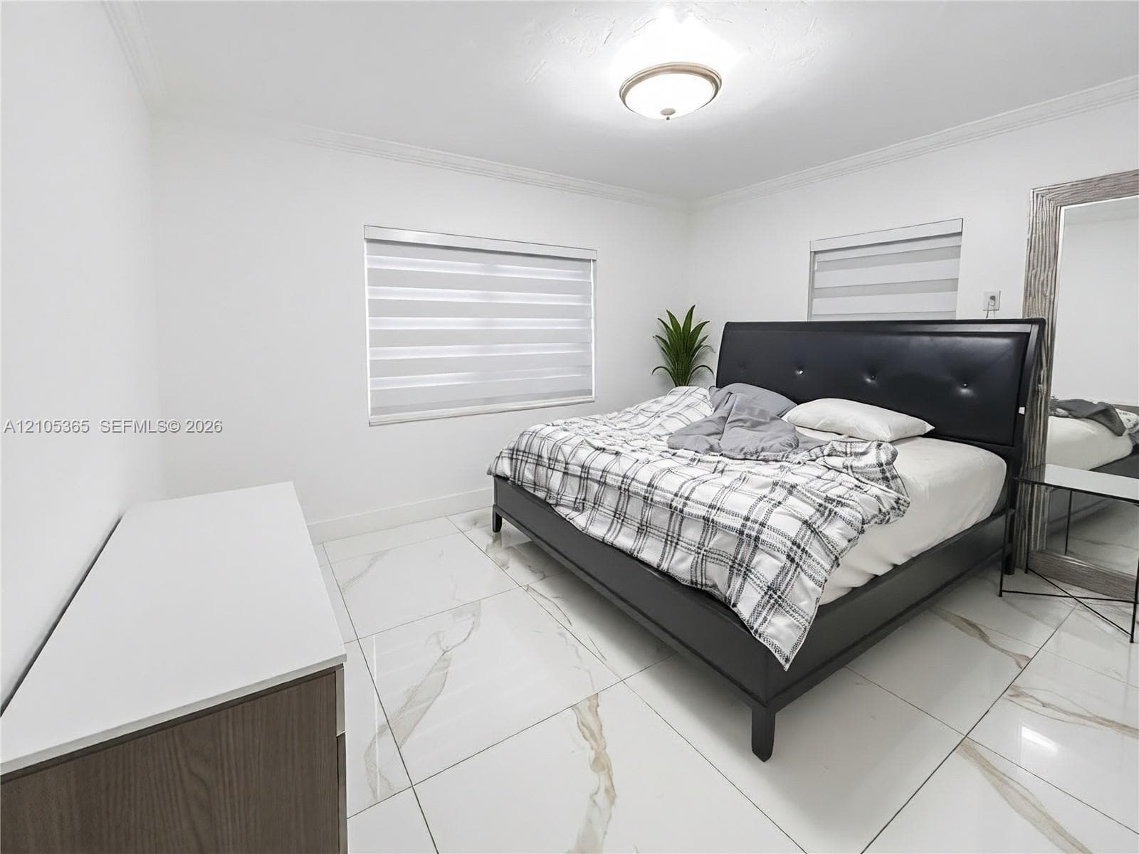 Spacious room featuring white tile flooring, crown molding, and two windows with blinds