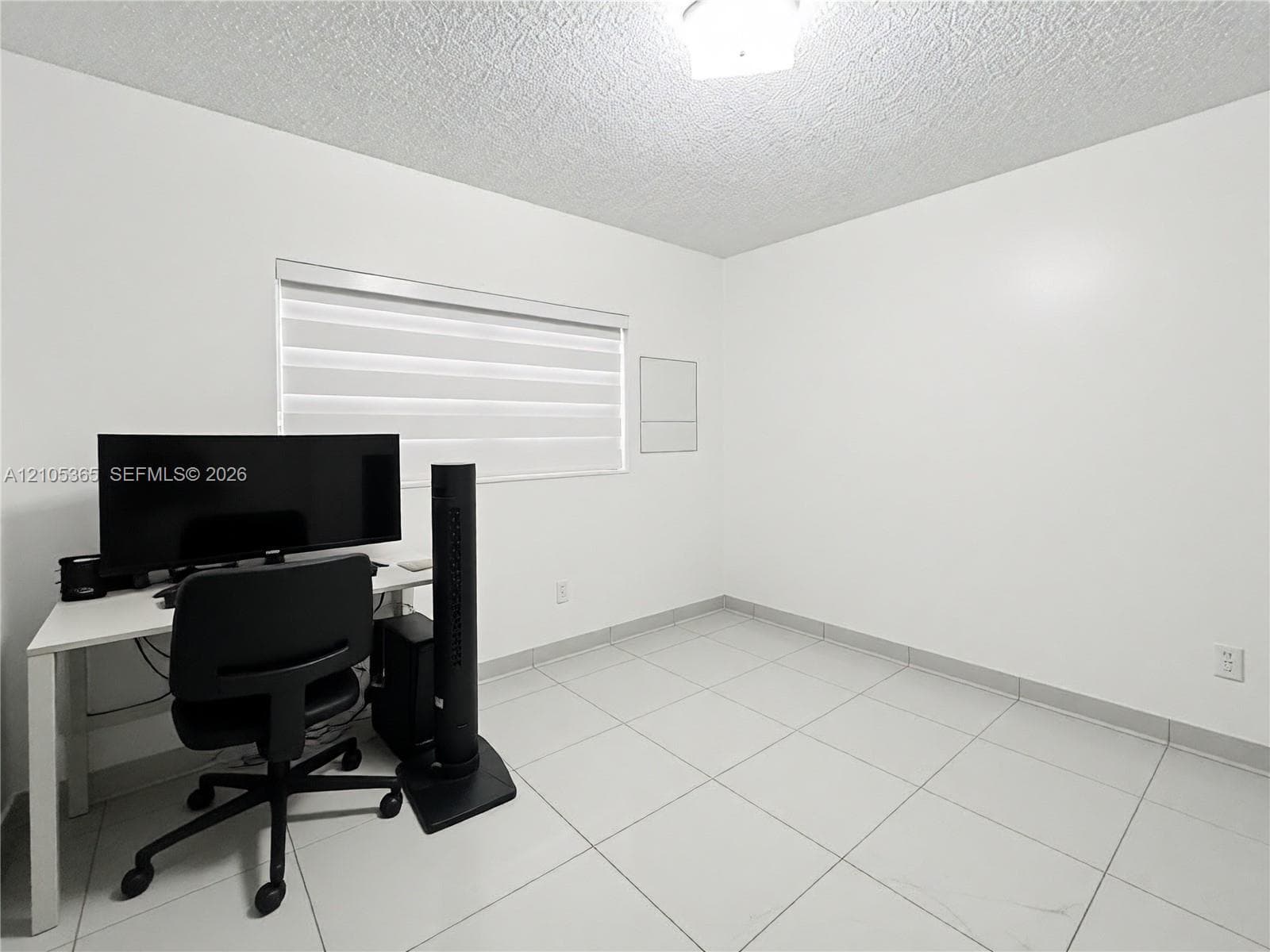 Recessed window with horizontal blinds, overhead lighting fixture, and tile flooring
