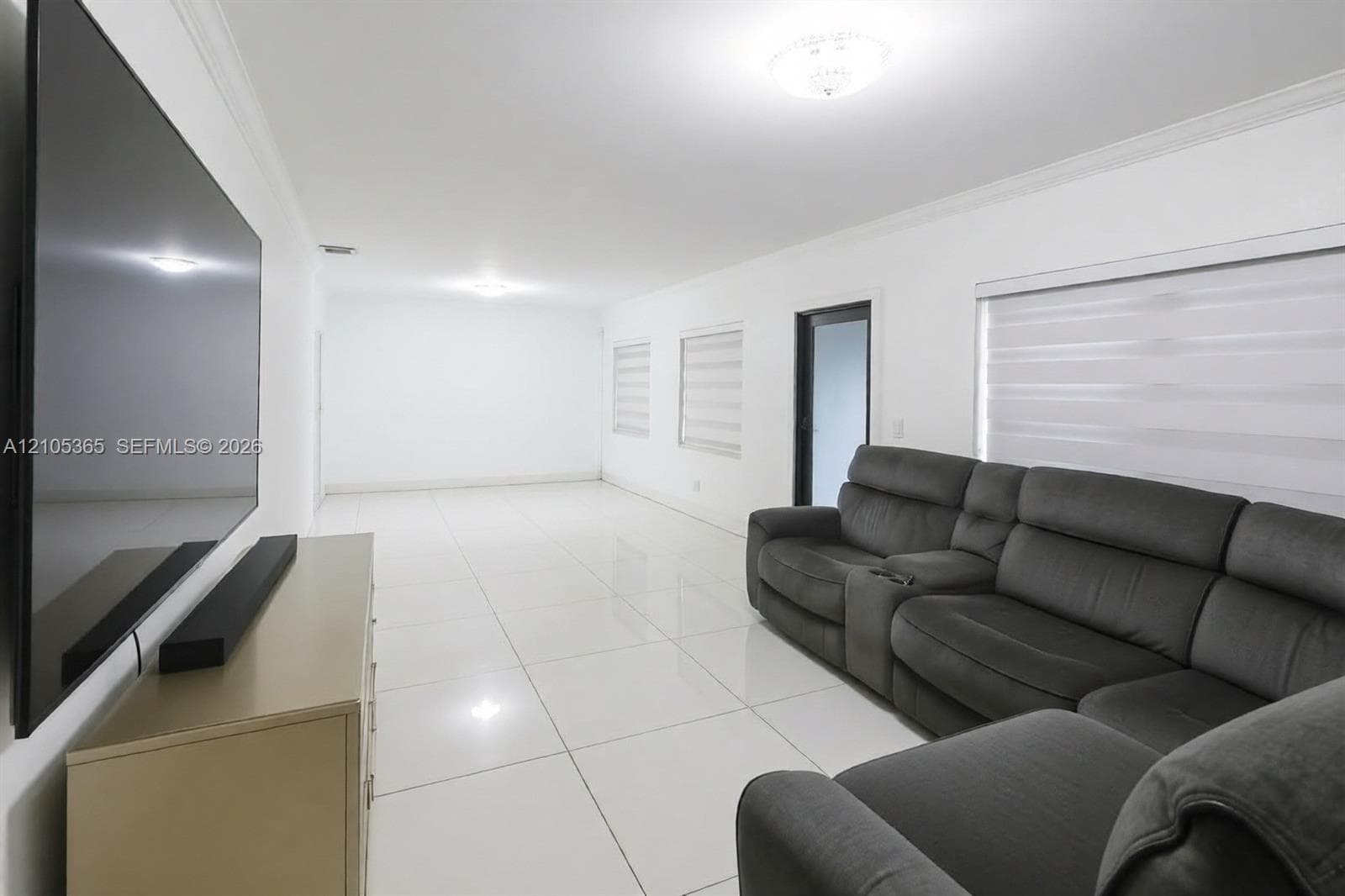 Spacious interior with white tile flooring and crown molding