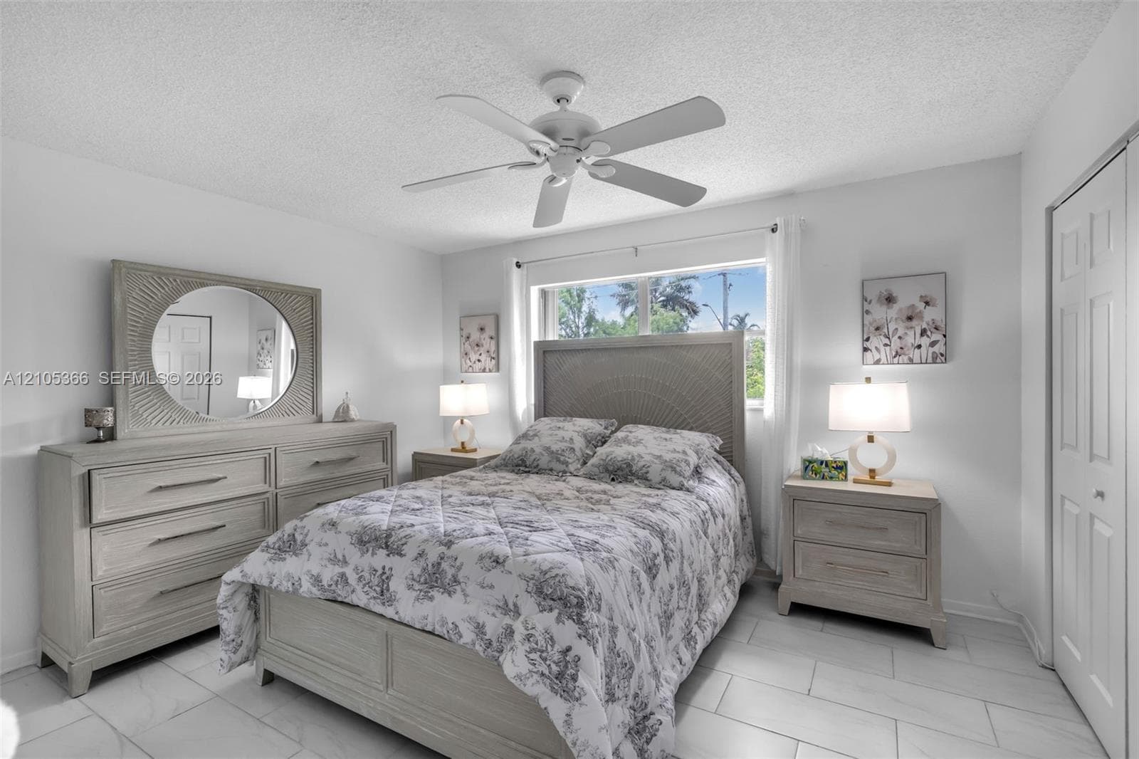 White tile flooring, ceiling fan, white paneled door, window with natural light, and a textured headboard