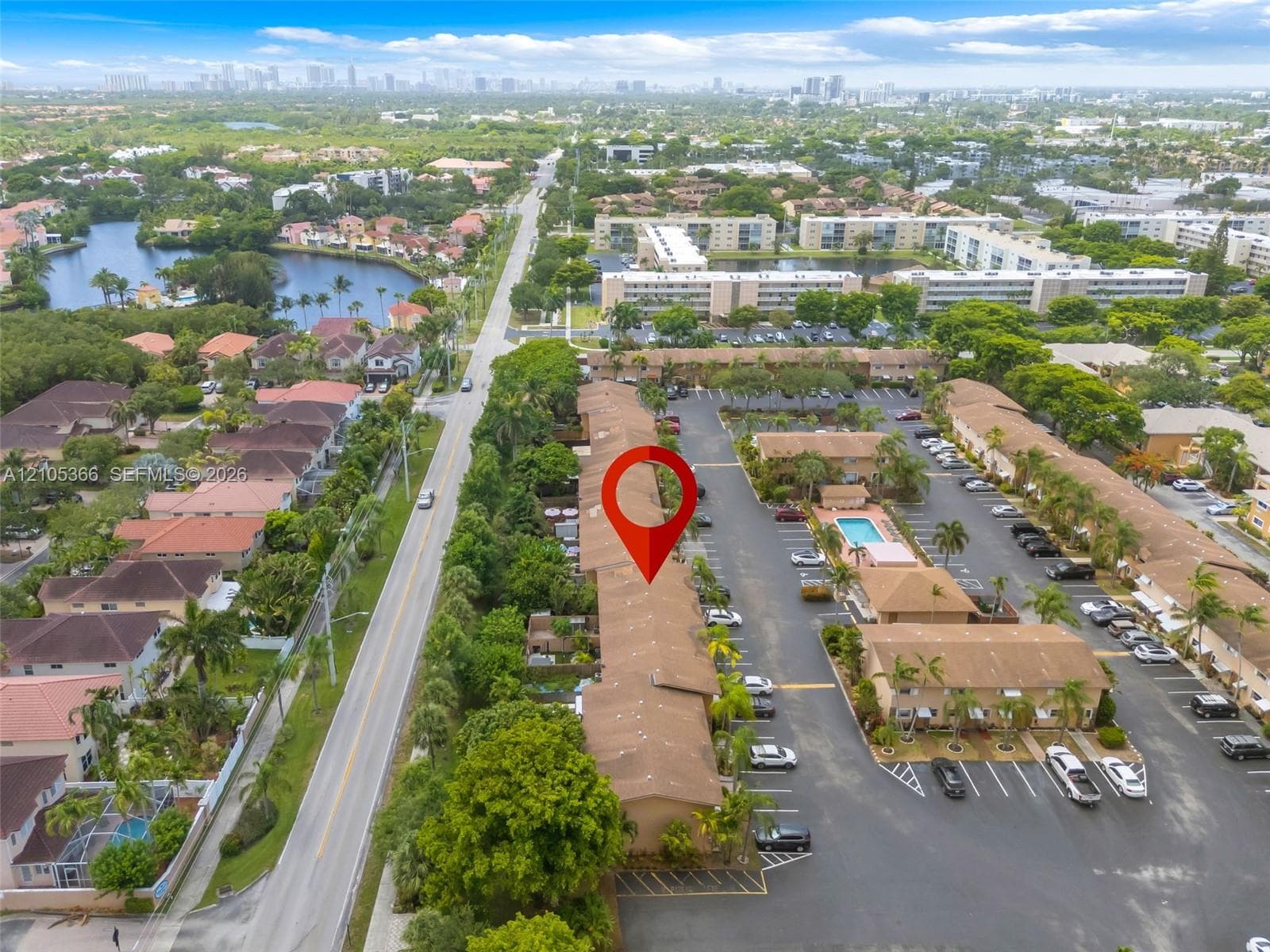 Community features a central swimming pool, paved parking areas, mature landscaping, and multiple residential buildings