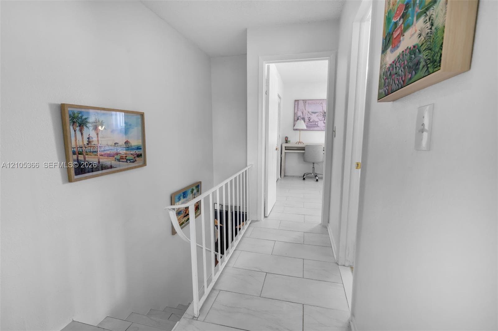 Hallway with tiled flooring and white painted walls, featuring a white metal stair railing