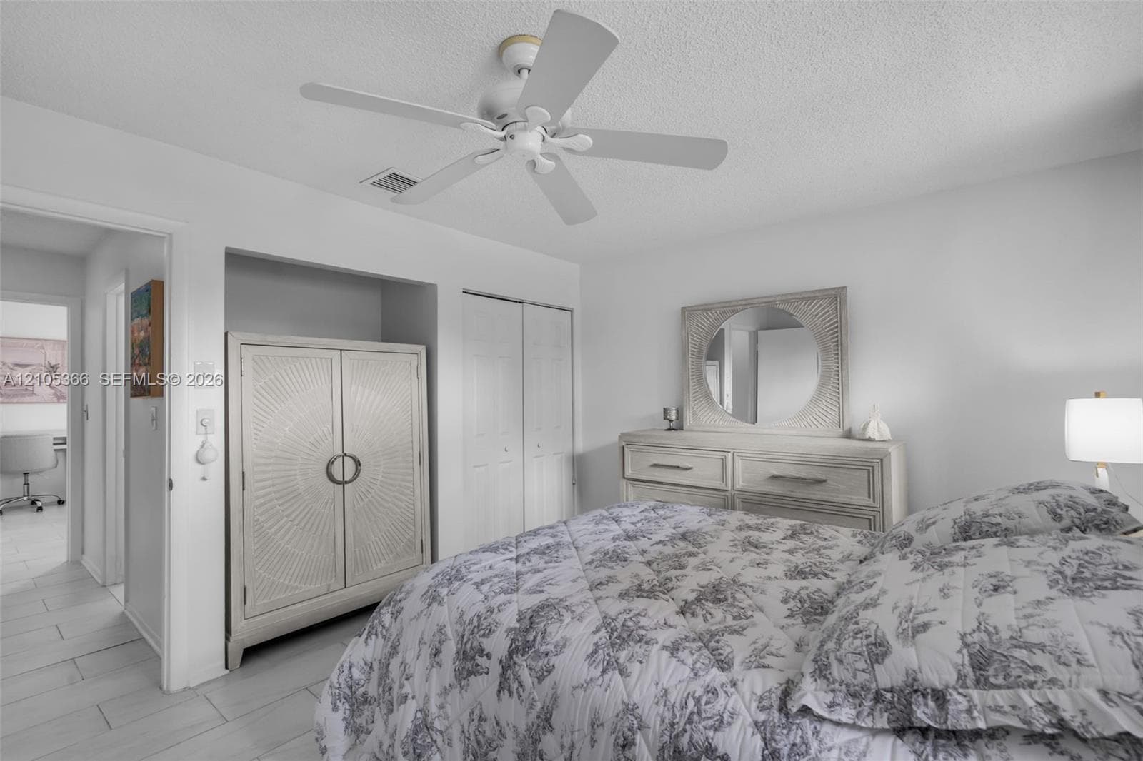 White ceiling fan, recessed wall niche, bifold closet doors, and wood-finish flooring