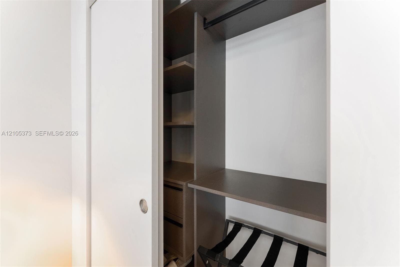 Custom closet system with integrated shelving, hanging rod, and sliding panel doors
