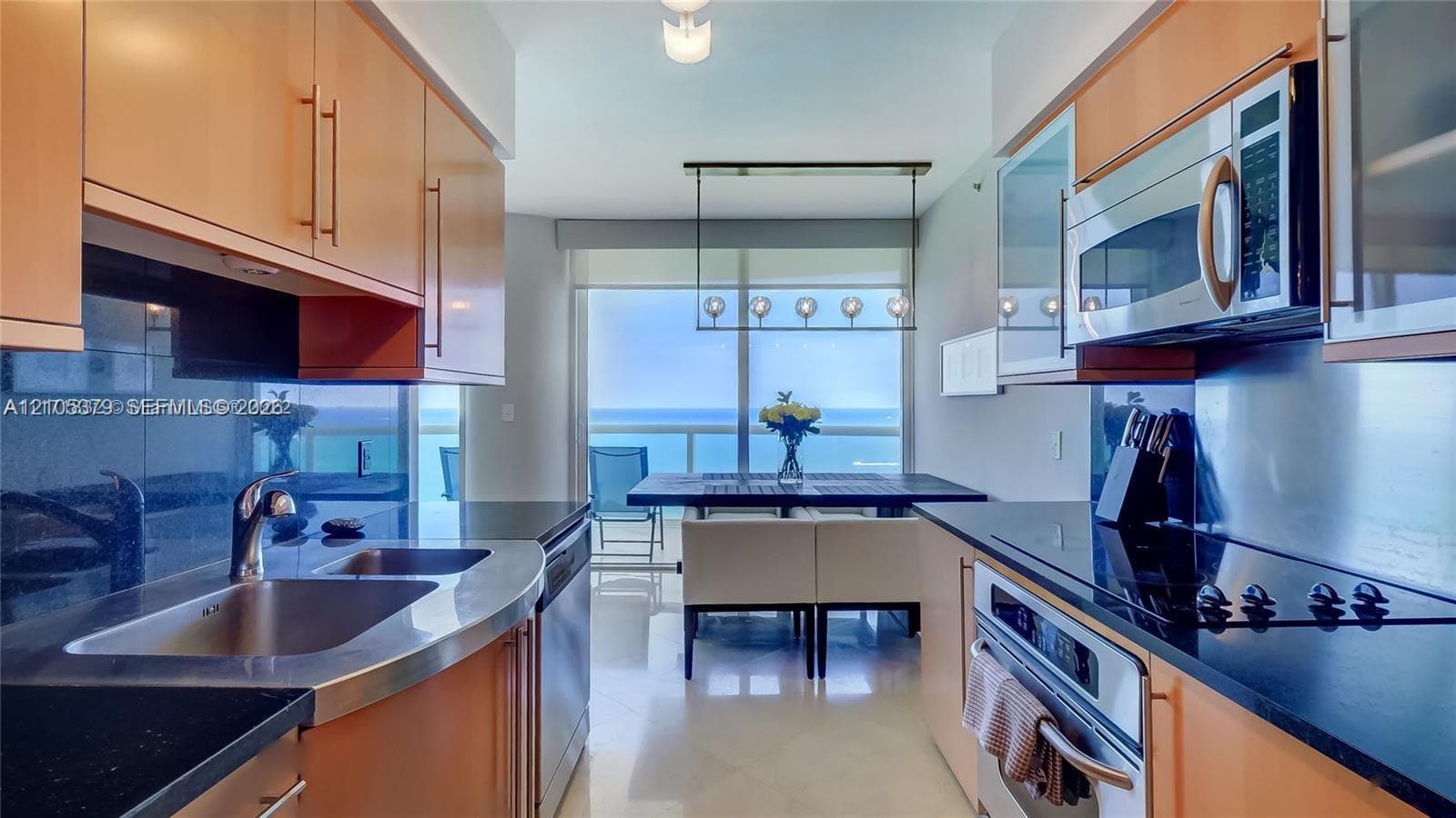 Kitchen featuring stainless steel appliances, wood-finish cabinetry, black countertops, and a built-in electric cooktop