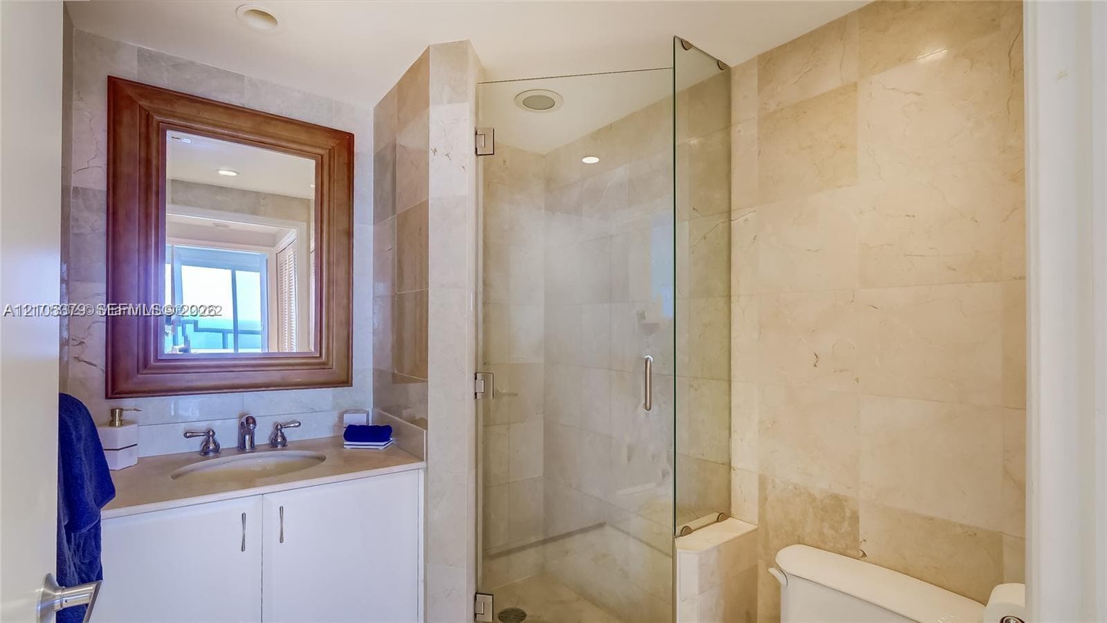 Built-in vanity with under-sink cabinetry, framed mirror, and a glass-enclosed shower