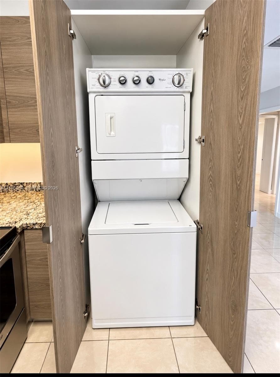 Stackable white washer and dryer unit within wood-finish cabinetry