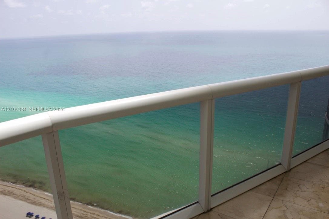 Balcony featuring a glass railing system, white handrail, and tile flooring