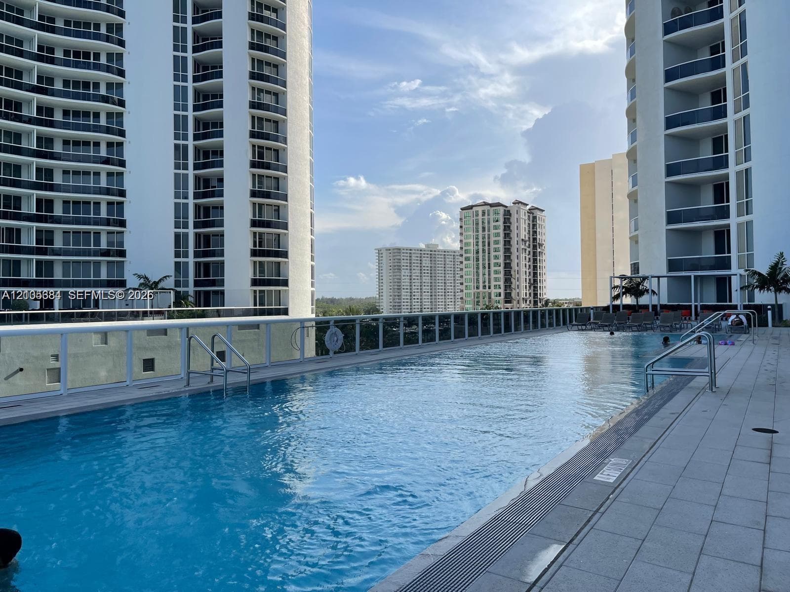 Rooftop swimming pool with surrounding tile decking and clear panel railing