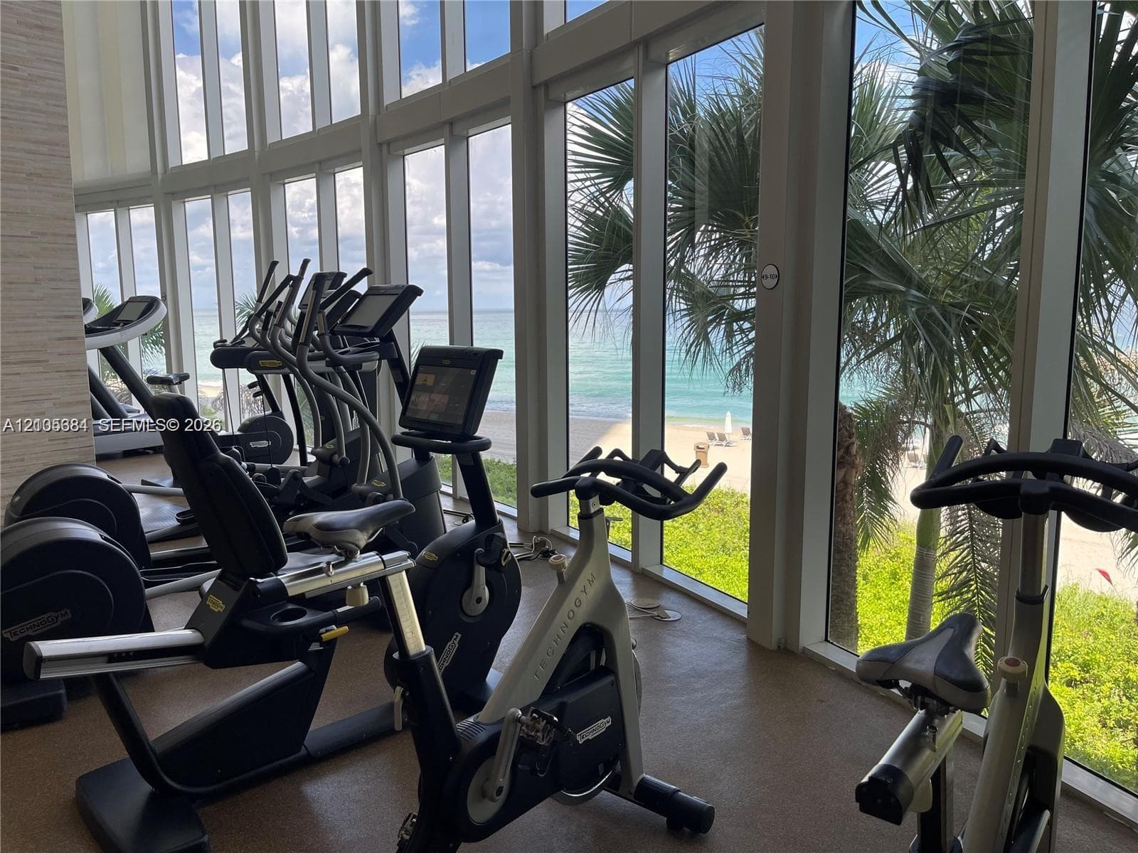 Fitness center featuring a selection of cardio equipment, full-height windows, and ocean scenery