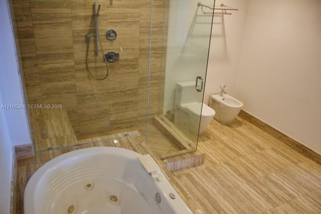 Walk-in shower with natural stone tile, glass enclosure, and built-in bench