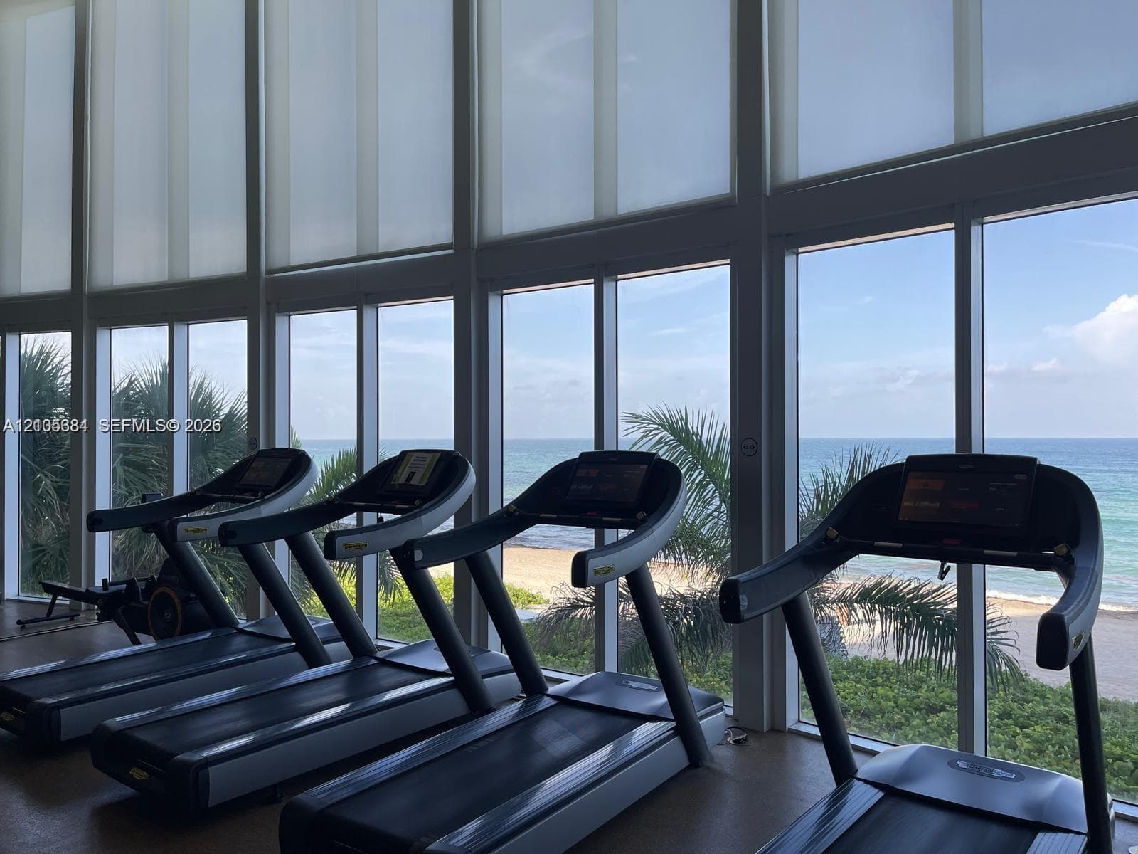 Floor-to-ceiling windows with roller shades, a scenic ocean backdrop, and integrated fitness equipment