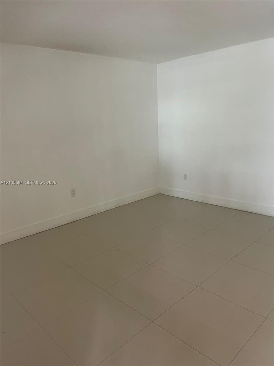 Spacious room featuring neutral painted walls, a neutral-toned tile floor with geometric layout, and recessed electrical outlets