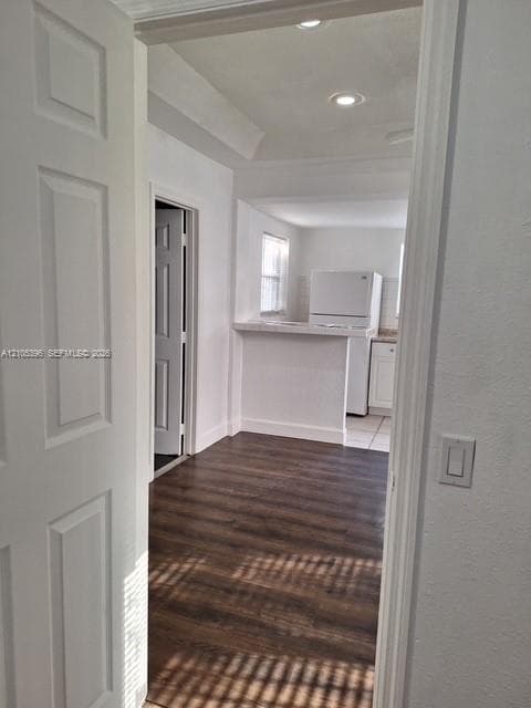 Wood-finish flooring, white paneled door, recessed lighting, and a kitchen pass-through with a countertop