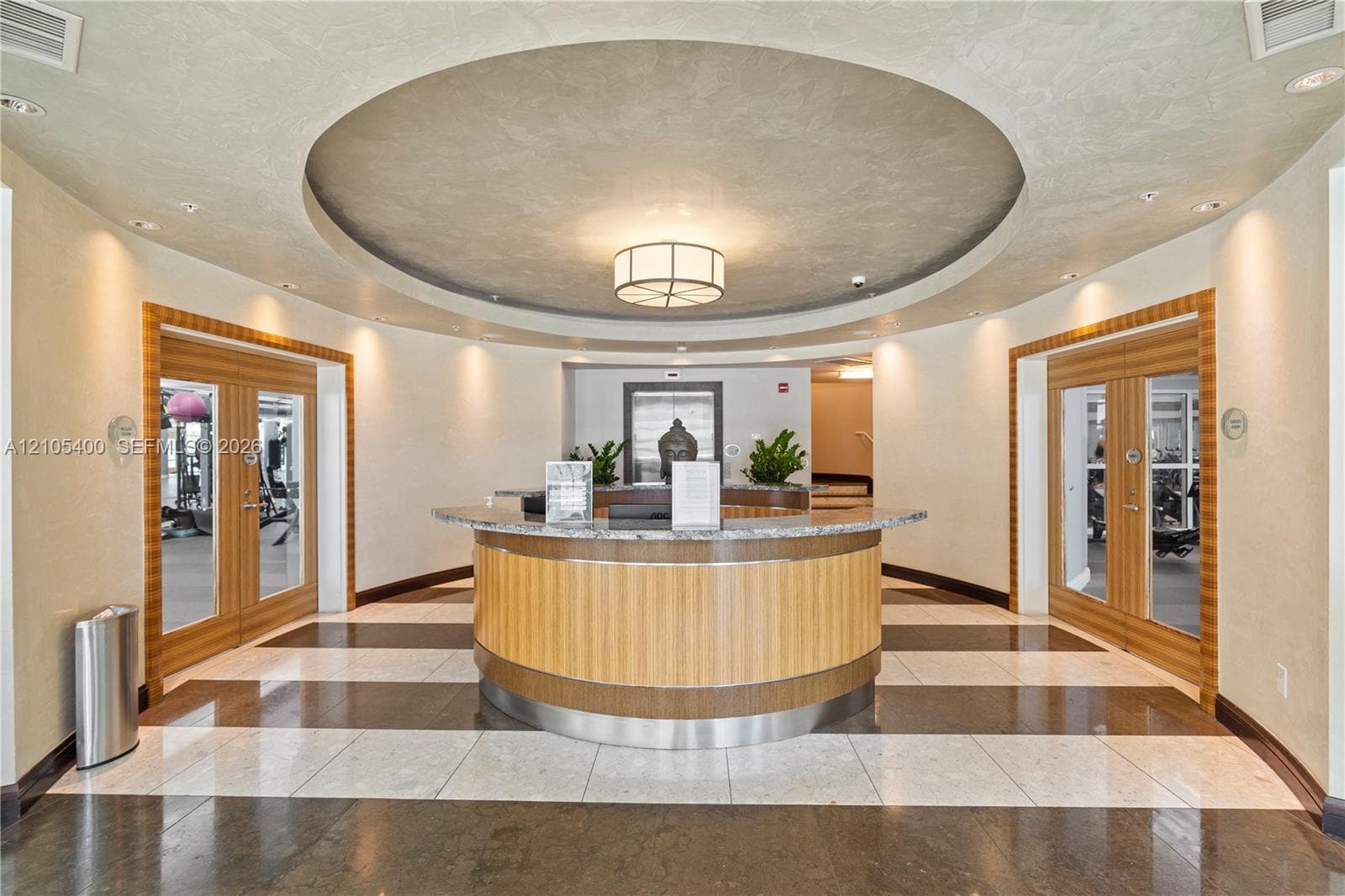 Circular reception area featuring a wood-finish desk with a stone countertop, recessed lighting, and a coffered ceiling