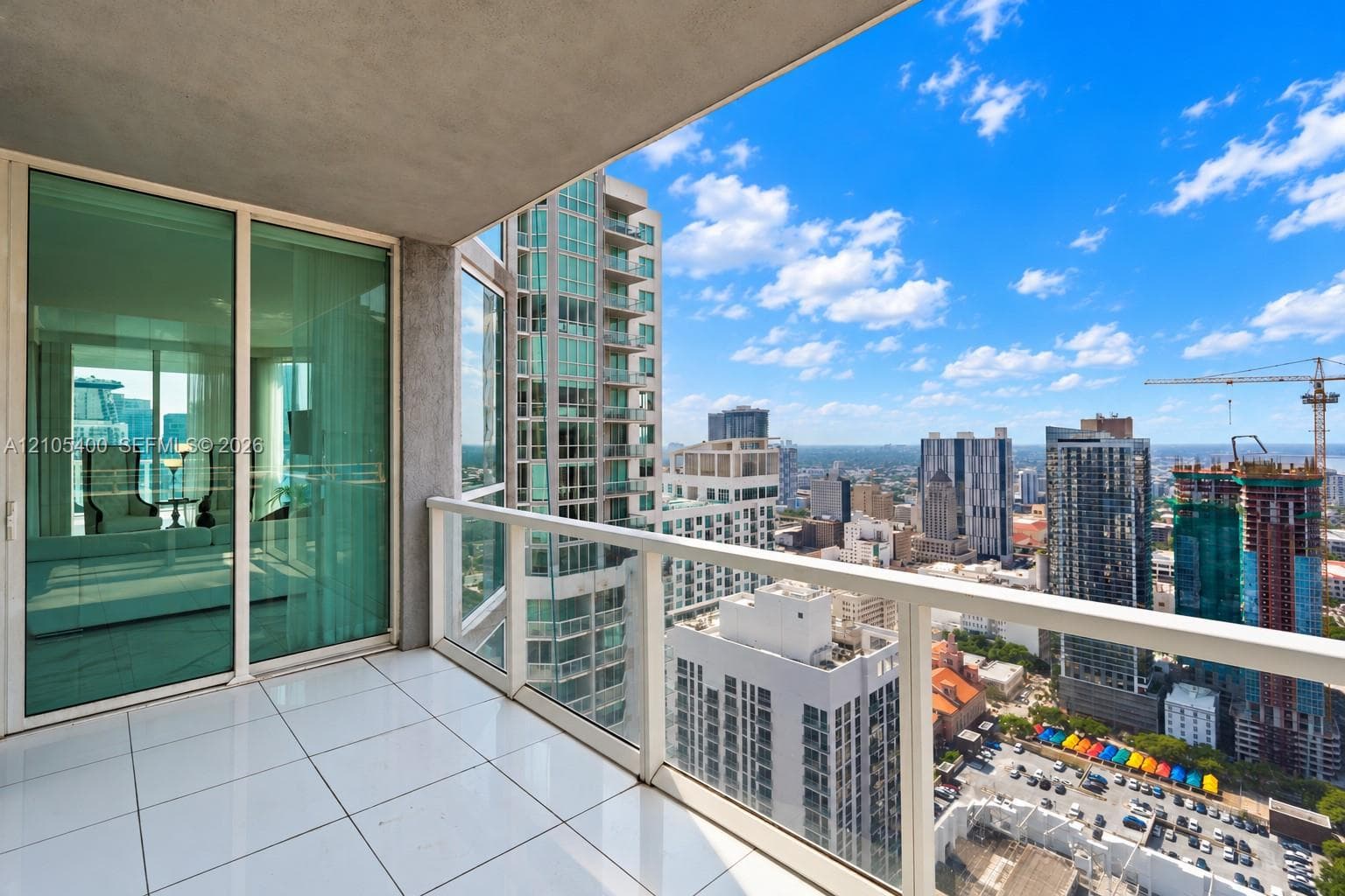 Expansive balcony with white tile flooring and glass railings, offering city scenery