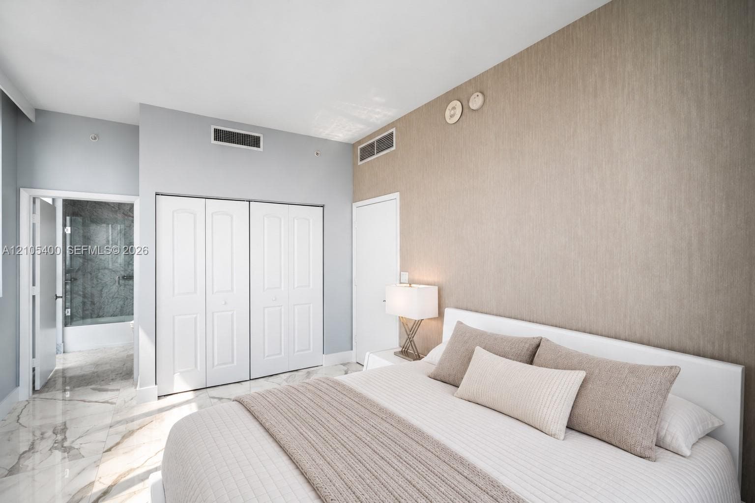 White bi-fold closet doors, textured wall covering, and marble-finish flooring