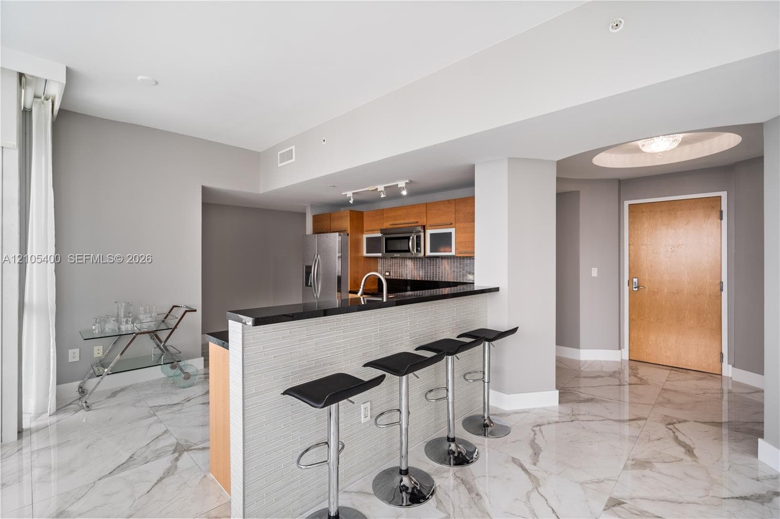 Kitchen featuring a breakfast bar with tile detailing, stone countertops, wood cabinetry, and stainless steel appliances