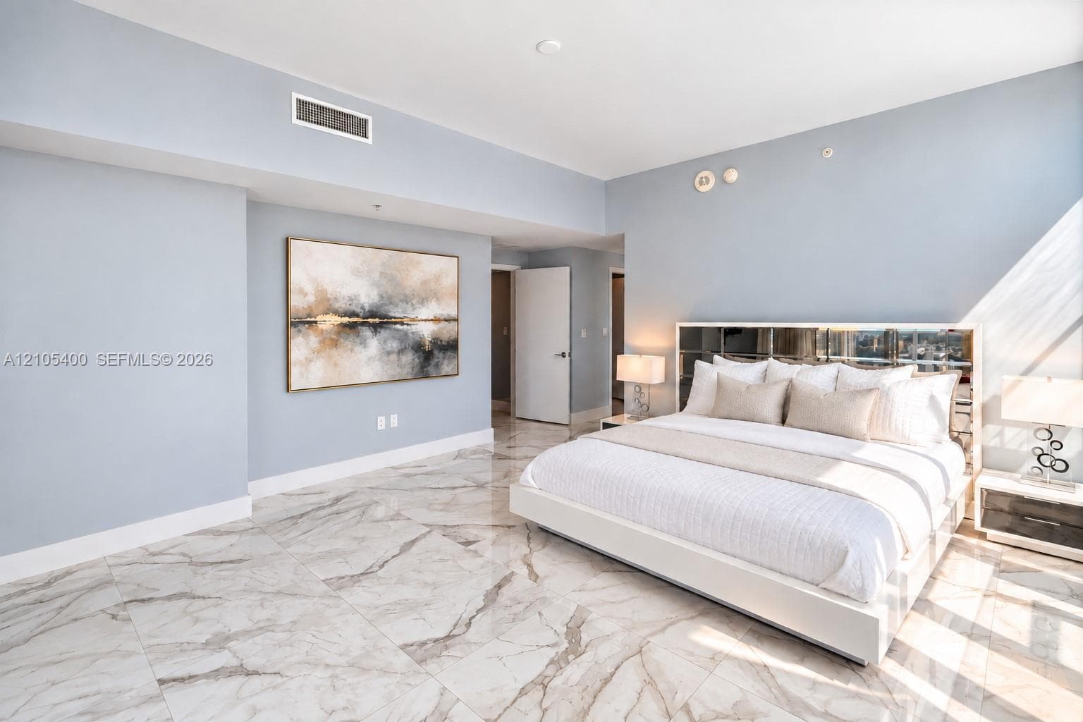 Spacious room featuring light-toned walls, recessed lighting, and large format flooring with natural veining