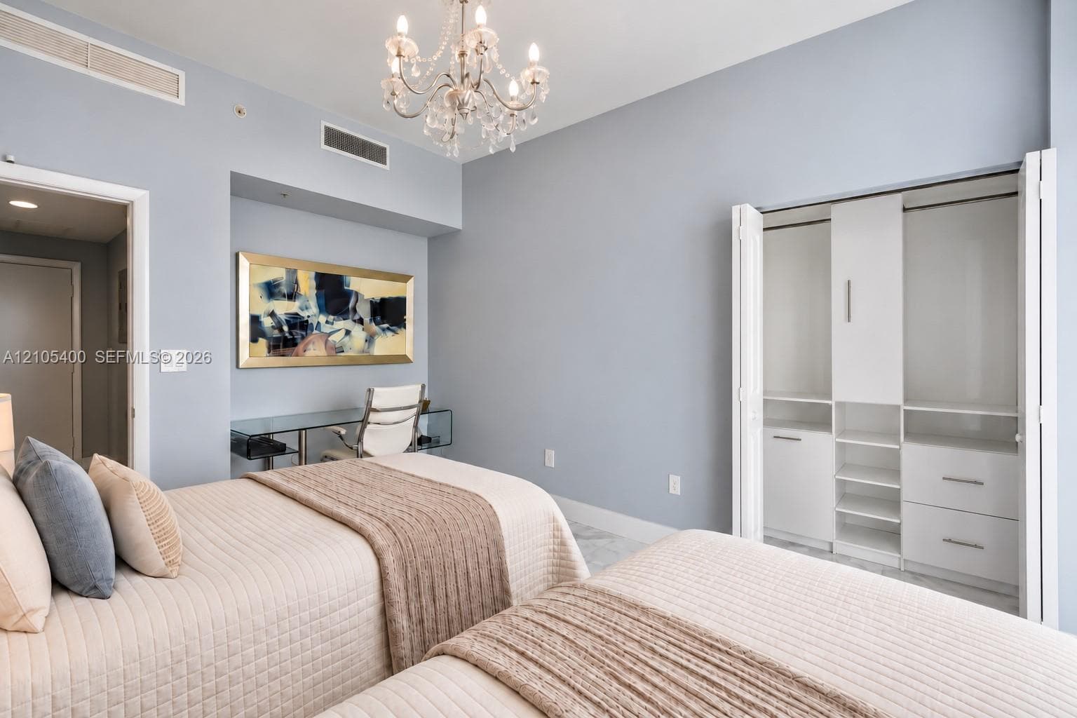 Recessed lighting, elegant chandelier, built-in desk, built-in closet organization system, light-toned wood-finish flooring