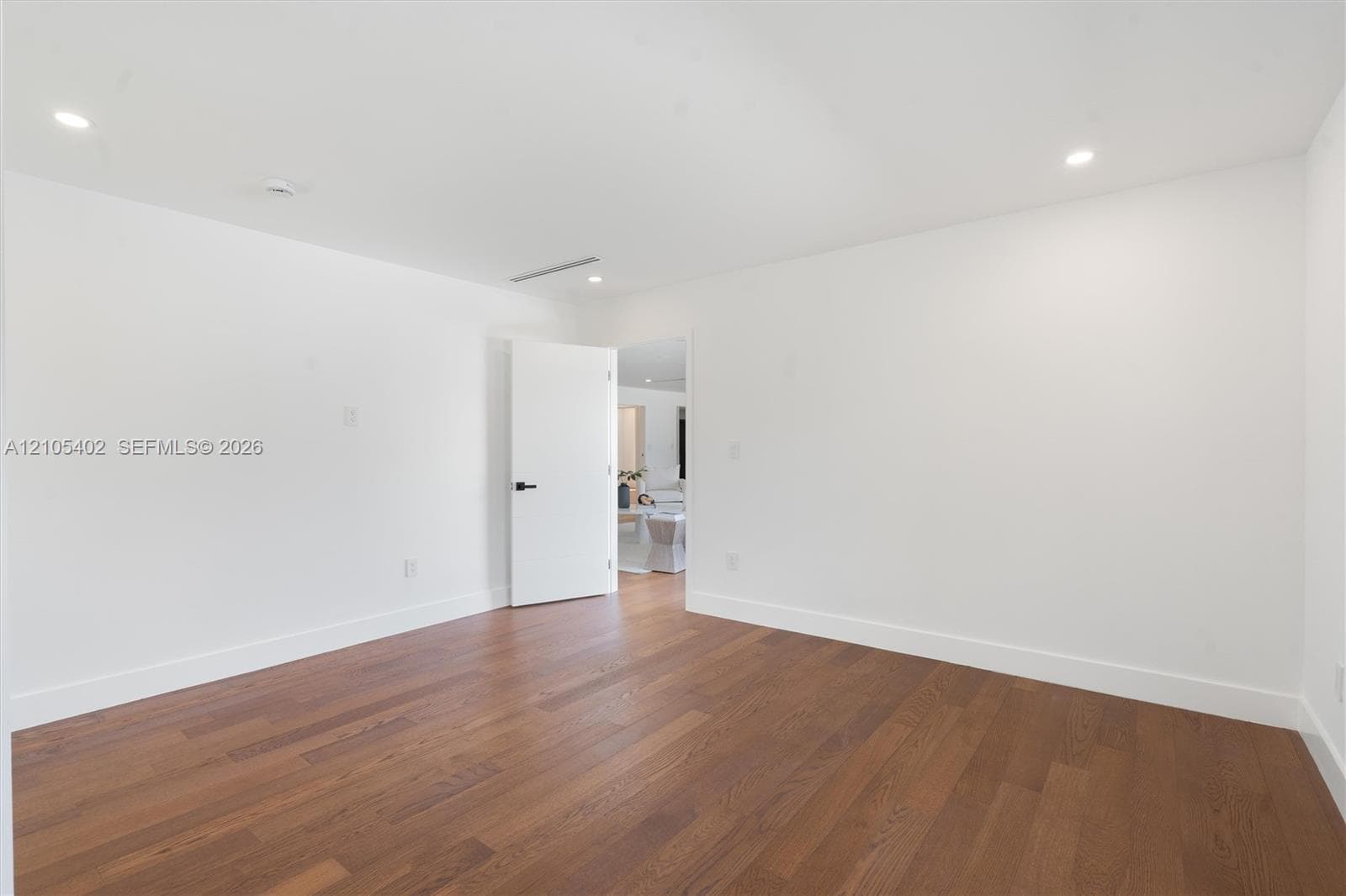 Interior room featuring wood-finish flooring, recessed lighting, and a white interior door with matte black hardware