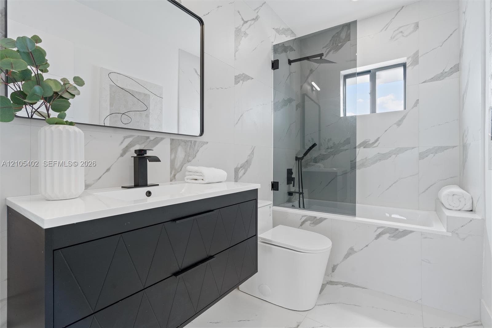 Modern floating vanity with a matte black geometric-patterned finish, white countertop, and black faucet