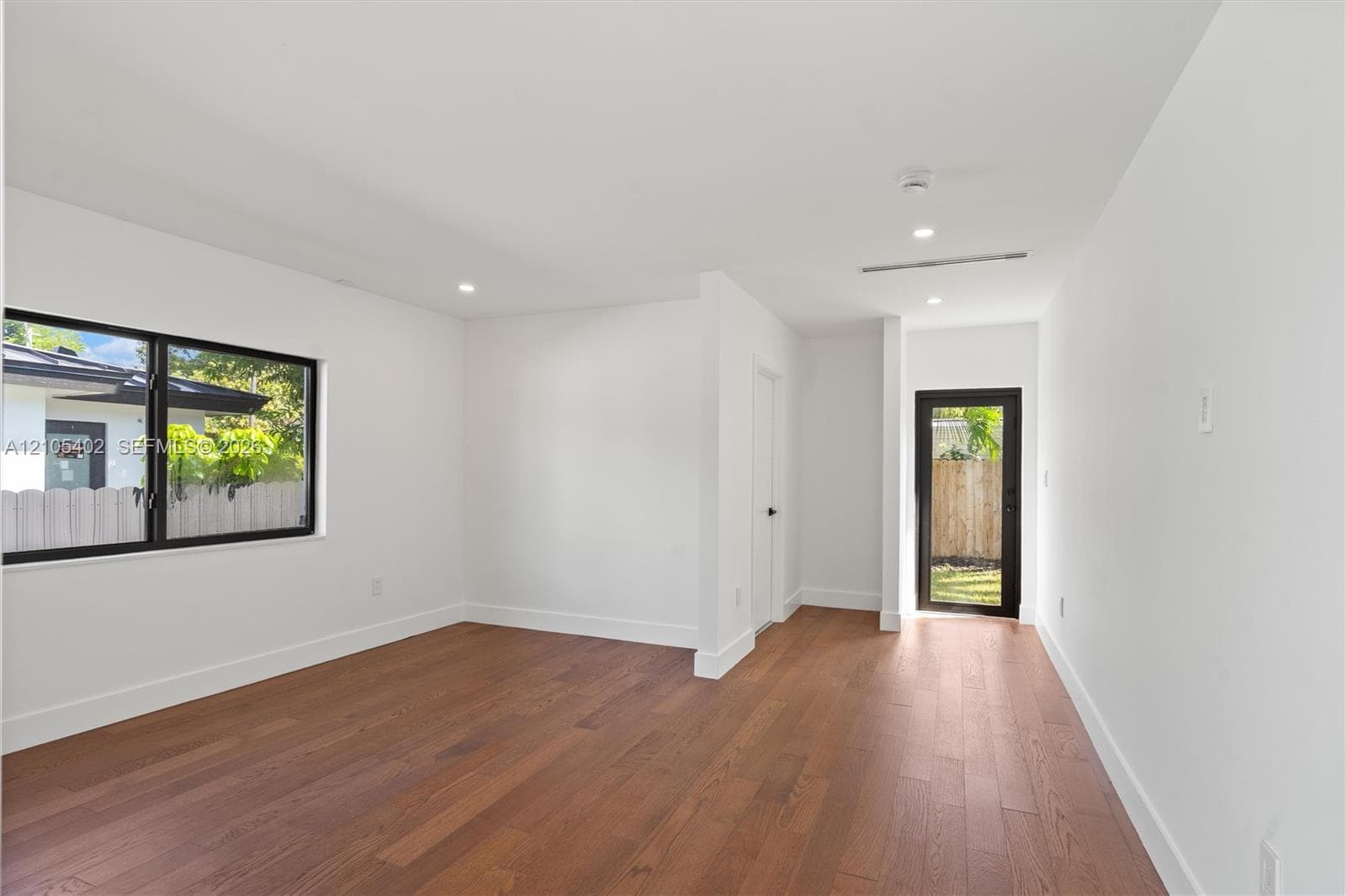 Interior space featuring wood-finish flooring, recessed lighting, and a glass-paneled exterior door with black framing