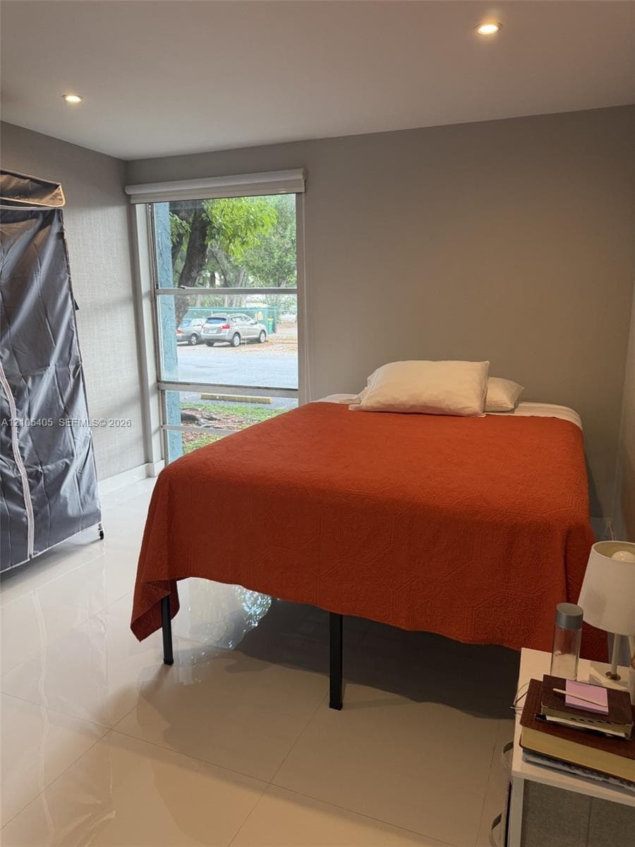 Recessed ceiling lighting, large window, white tile flooring, and neutral wall tones