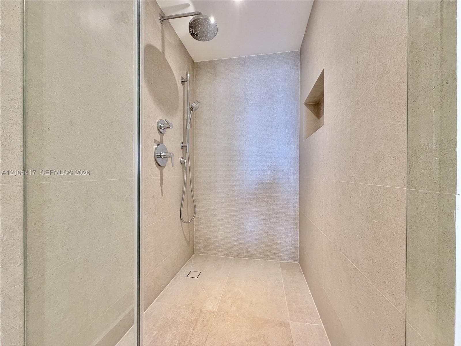 Walk-in shower with full-height tile, recessed niche, rainfall showerhead, and handheld shower fixture