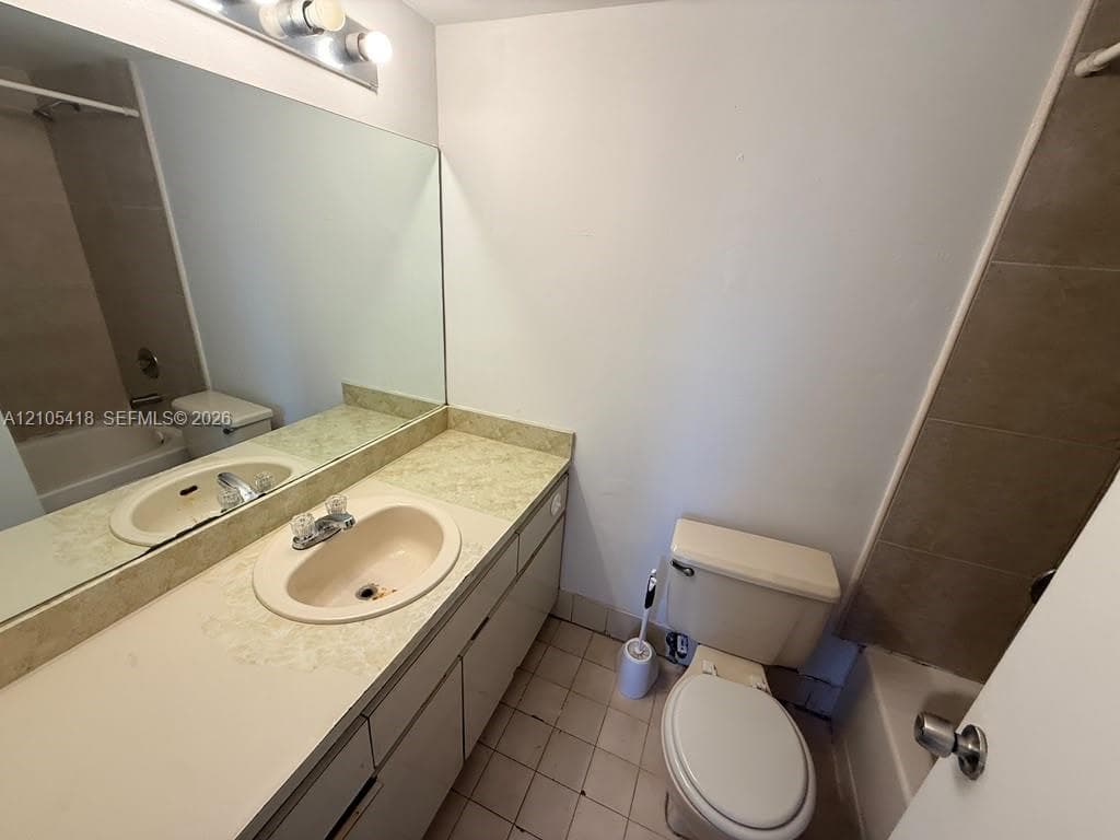 Extended vanity with a single basin sink, wall-mounted mirror, and overhead lighting fixture