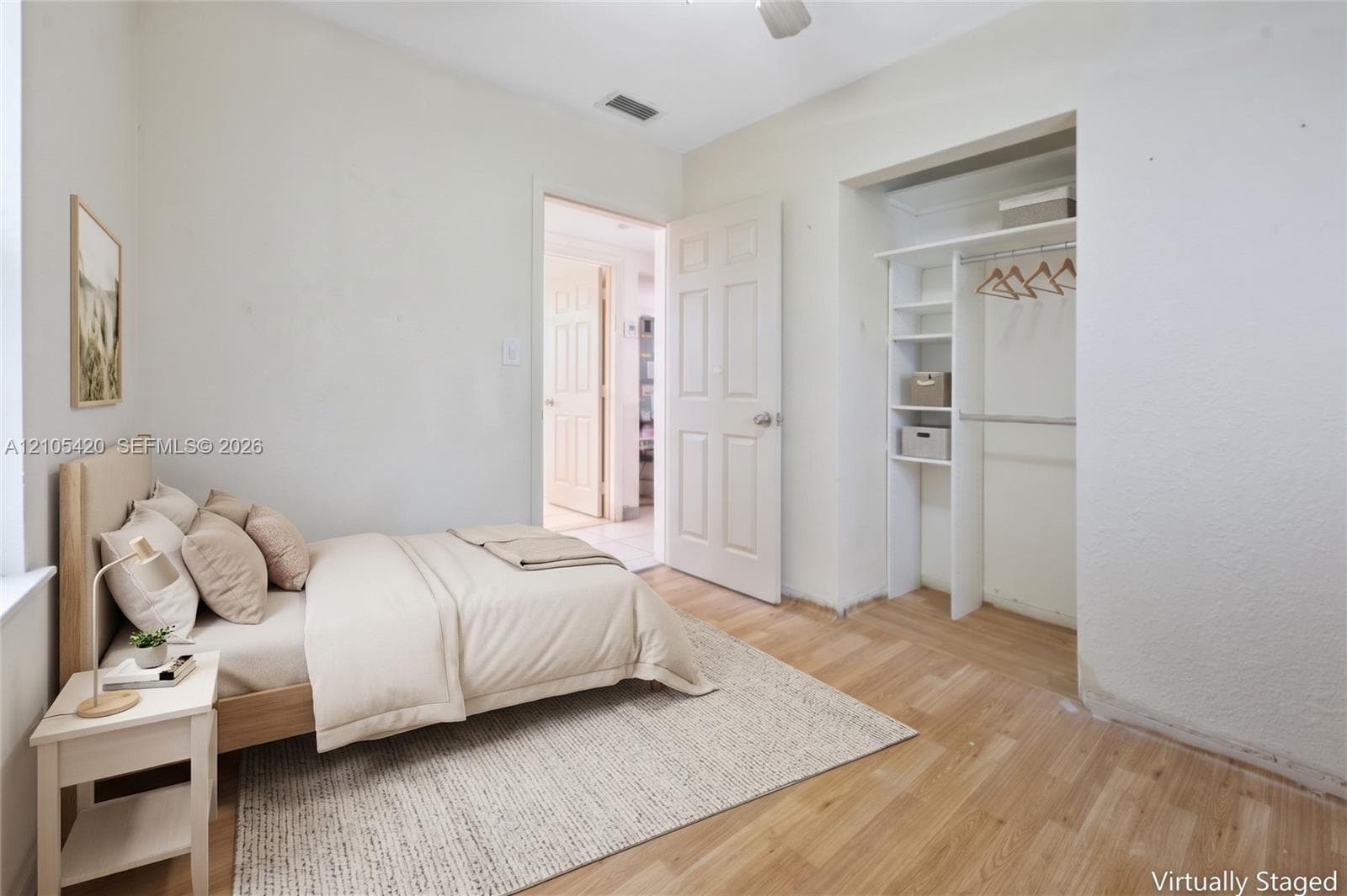 Recessed closet with integrated shelving, wood-finish flooring, and a paneled door