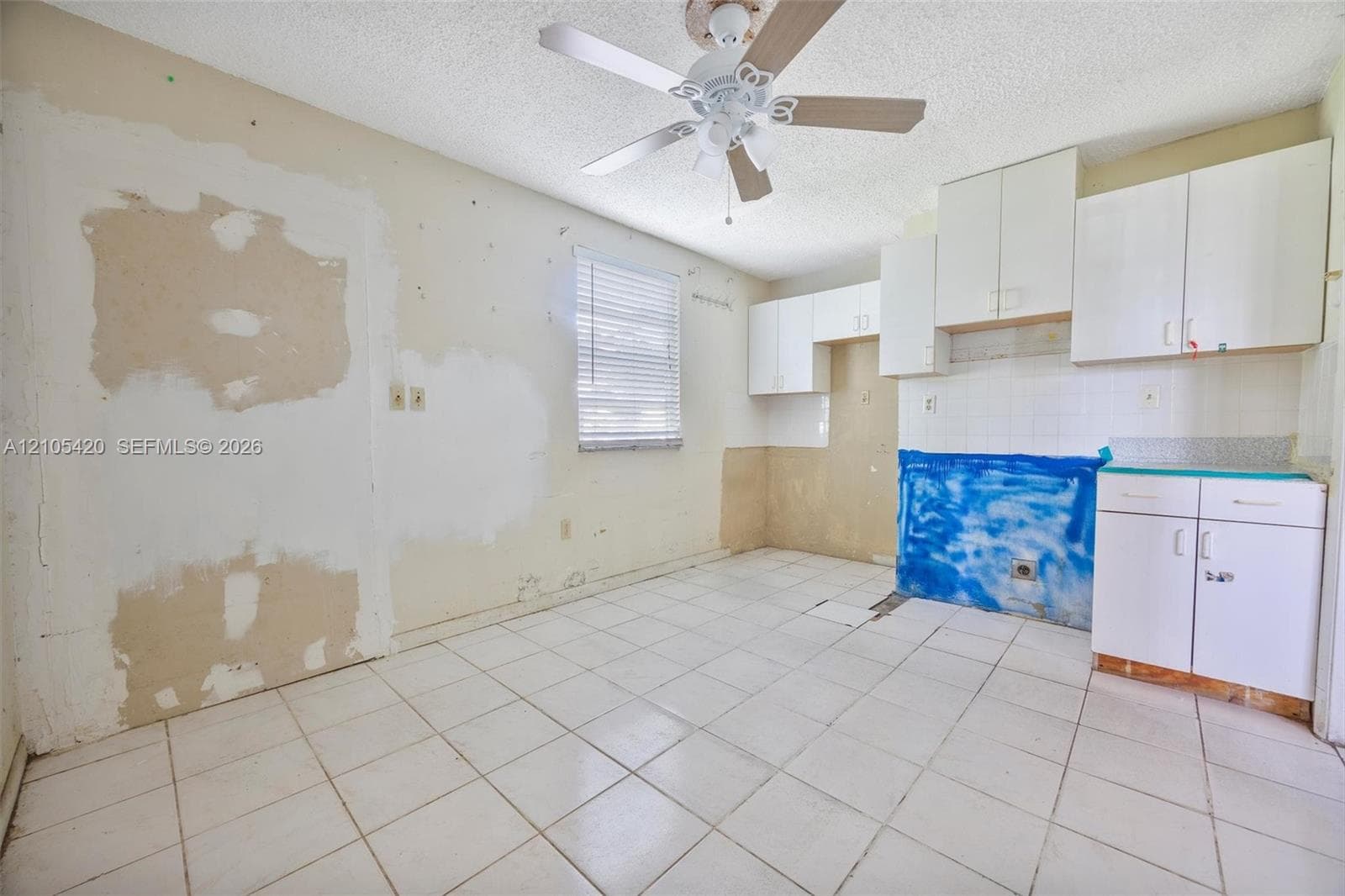 White cabinetry, tiled flooring, and a ceiling fan