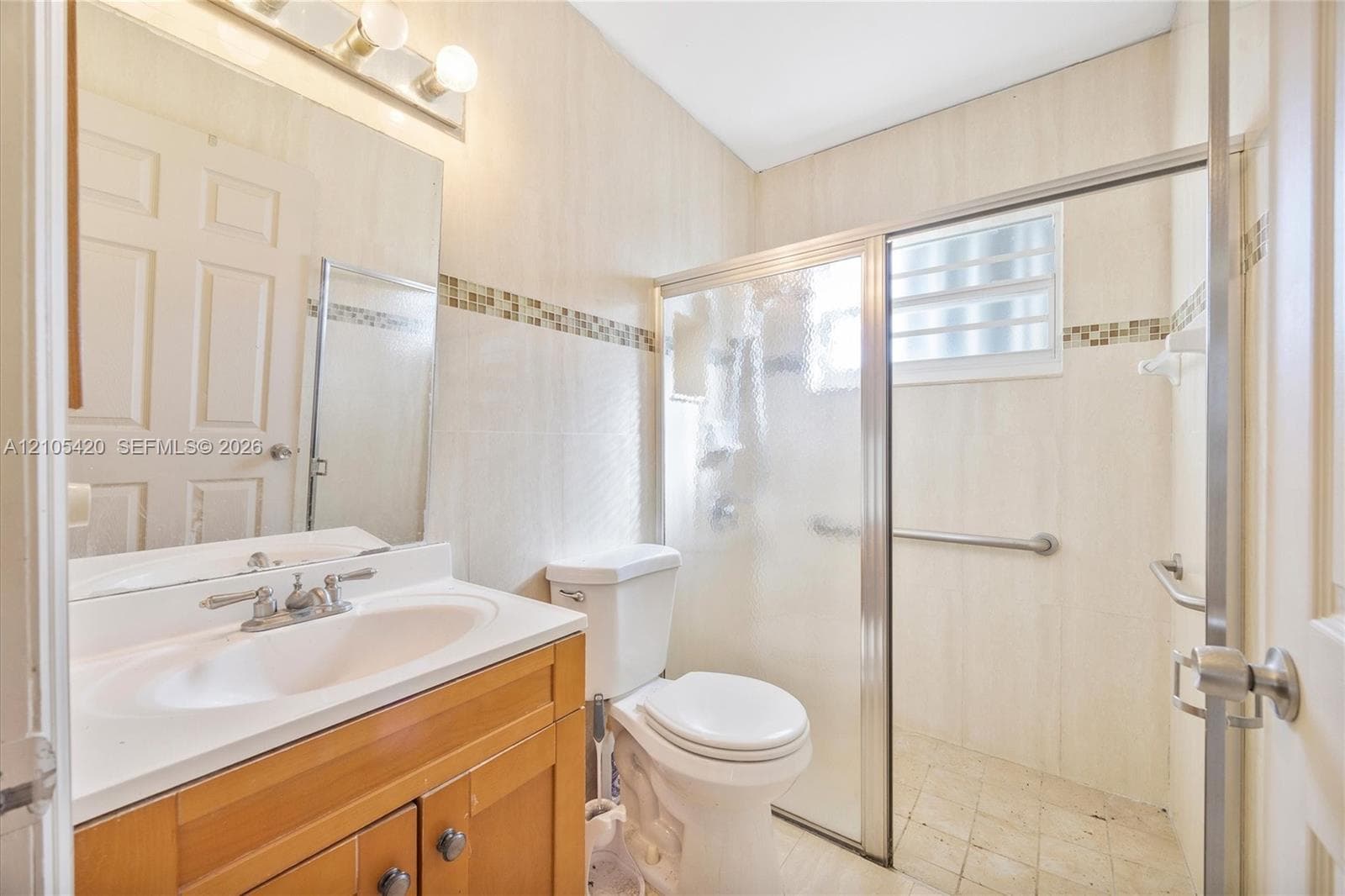Full vanity with a single basin sink, wood-finish cabinetry, and a mirrored wall