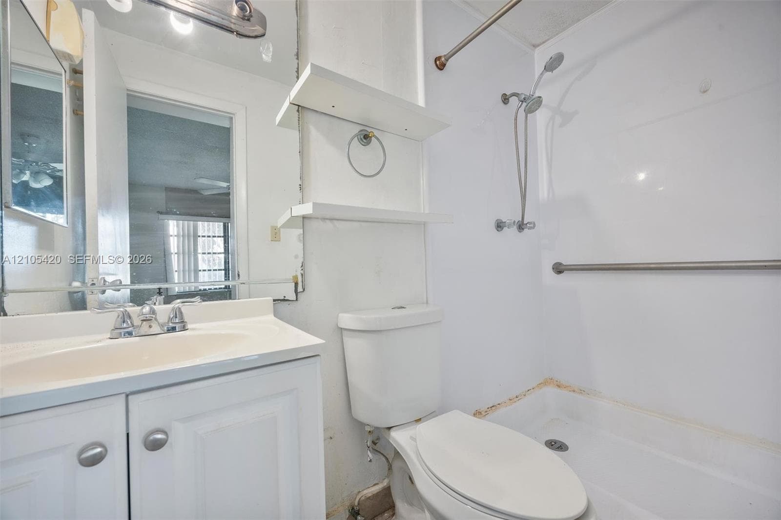 White vanity with integrated sink, chrome faucet, and mirrored medicine cabinet