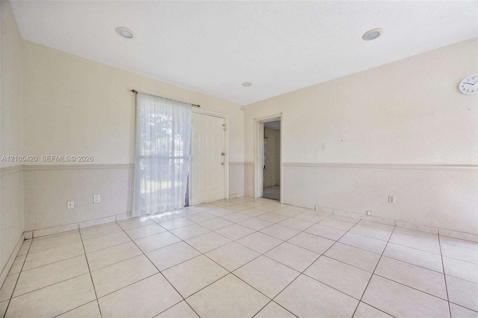 Tile flooring, recessed lighting, white interior door, and window with sheer curtain