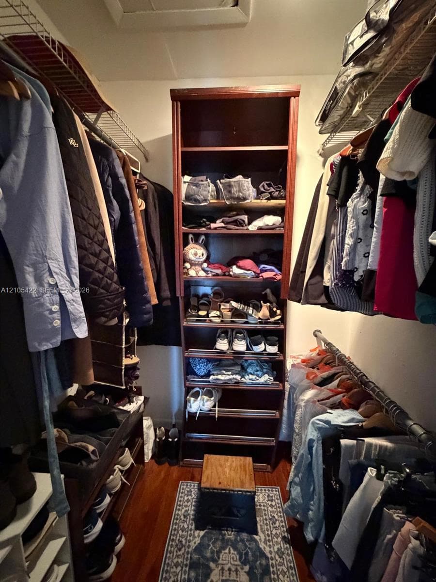 Walk-in closet featuring wood-finish flooring, built-in shelving unit, and integrated wire racking systems