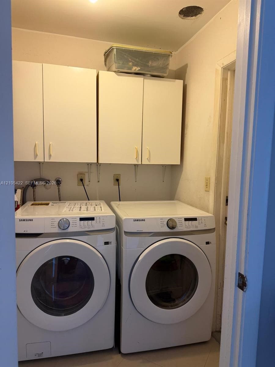 Dedicated laundry space featuring wall-mounted white cabinetry, recessed ceiling lighting, and dedicated water and electrical hookups