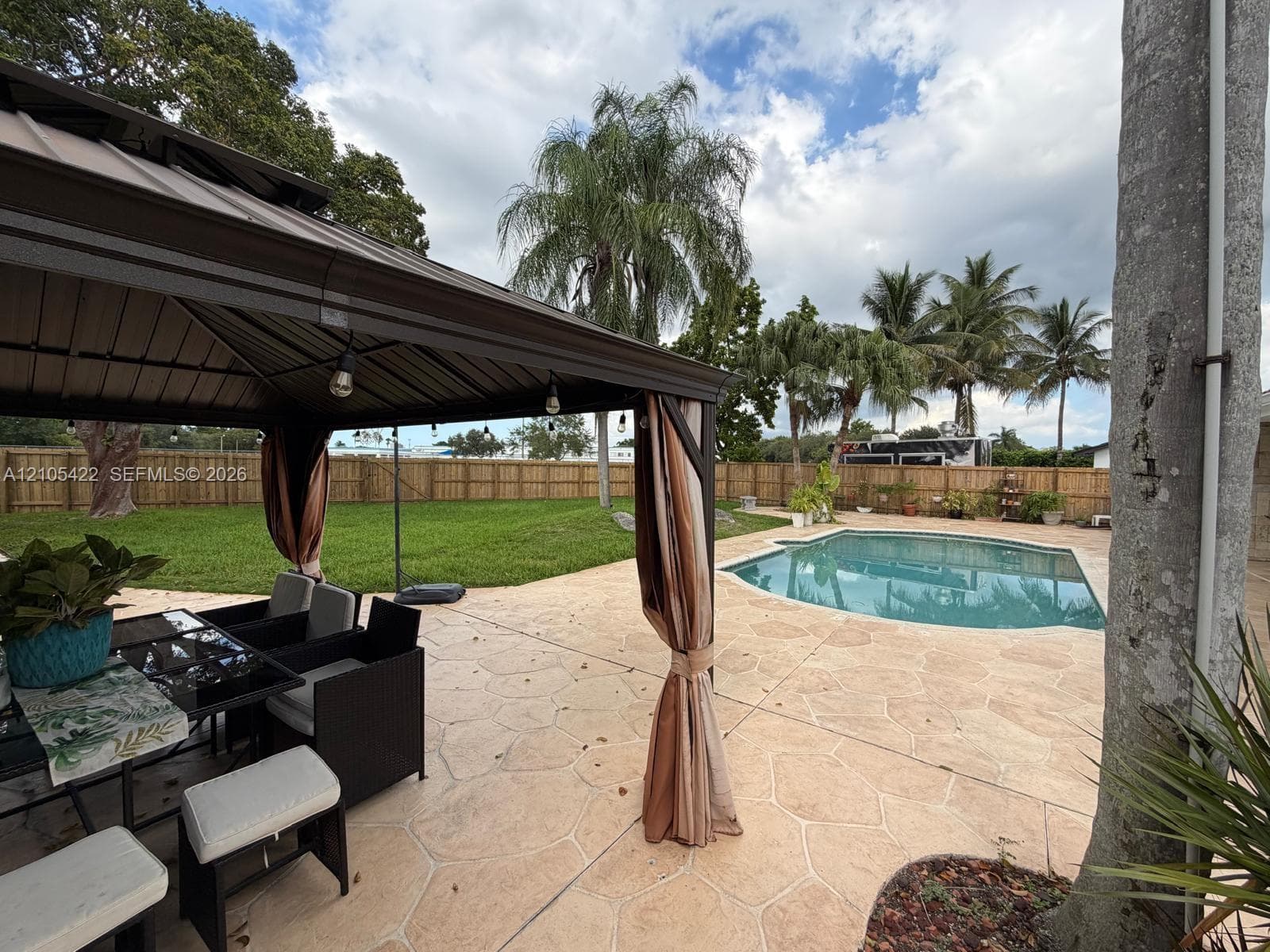 Backyard featuring a metal-frame gazebo, stamped concrete patio, inground swimming pool, and privacy wood fencing