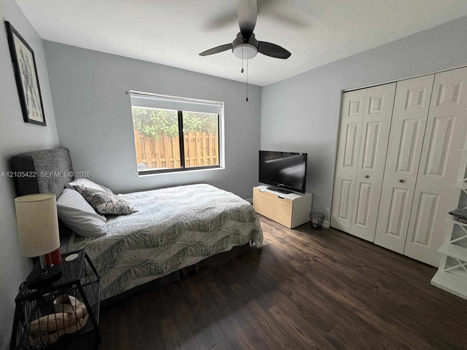 Room featuring wood-finish flooring, dual-panel closet doors, and a ceiling fan with integrated lighting